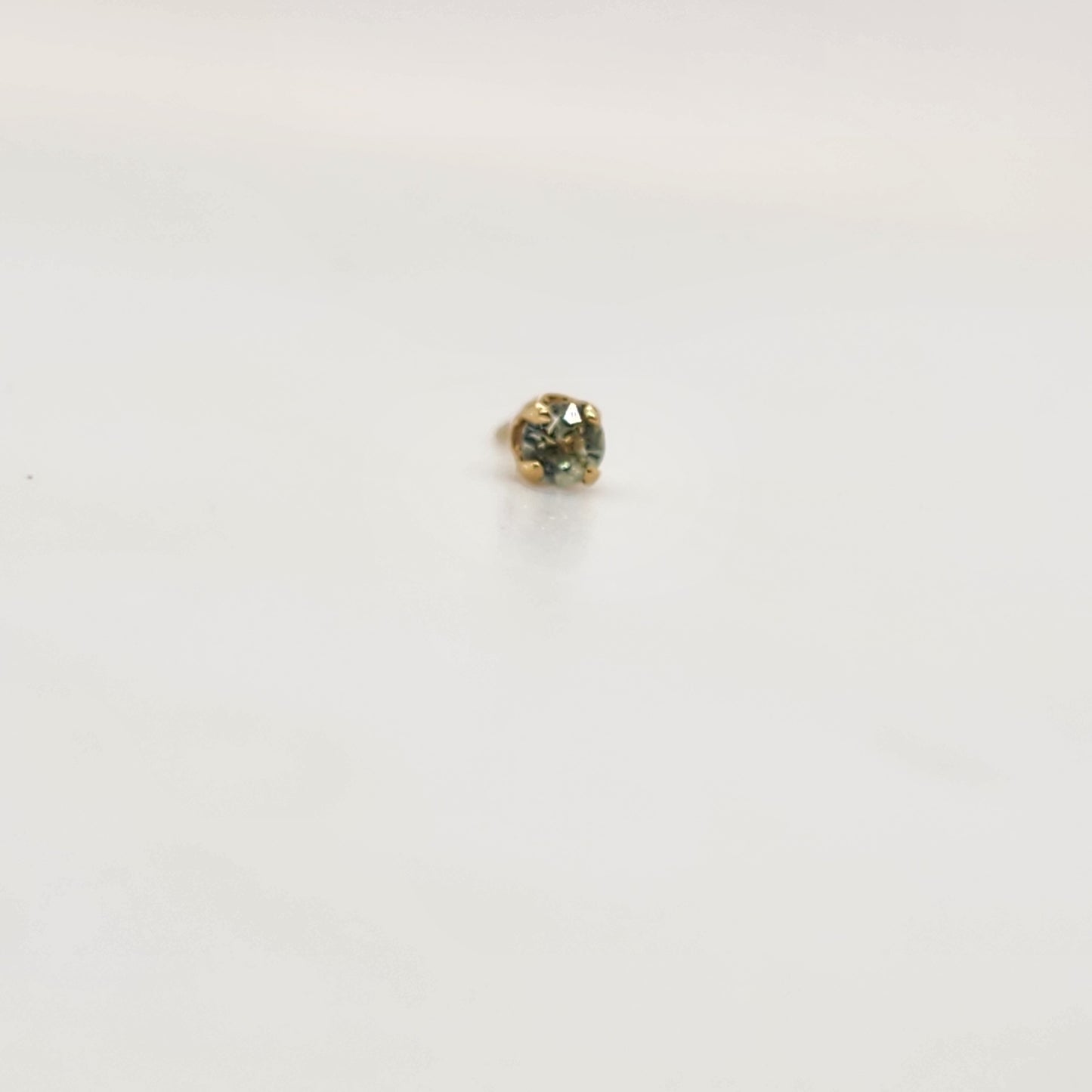 A delicate 2mm green montana sapphire in a 4 prong yellow gold setting