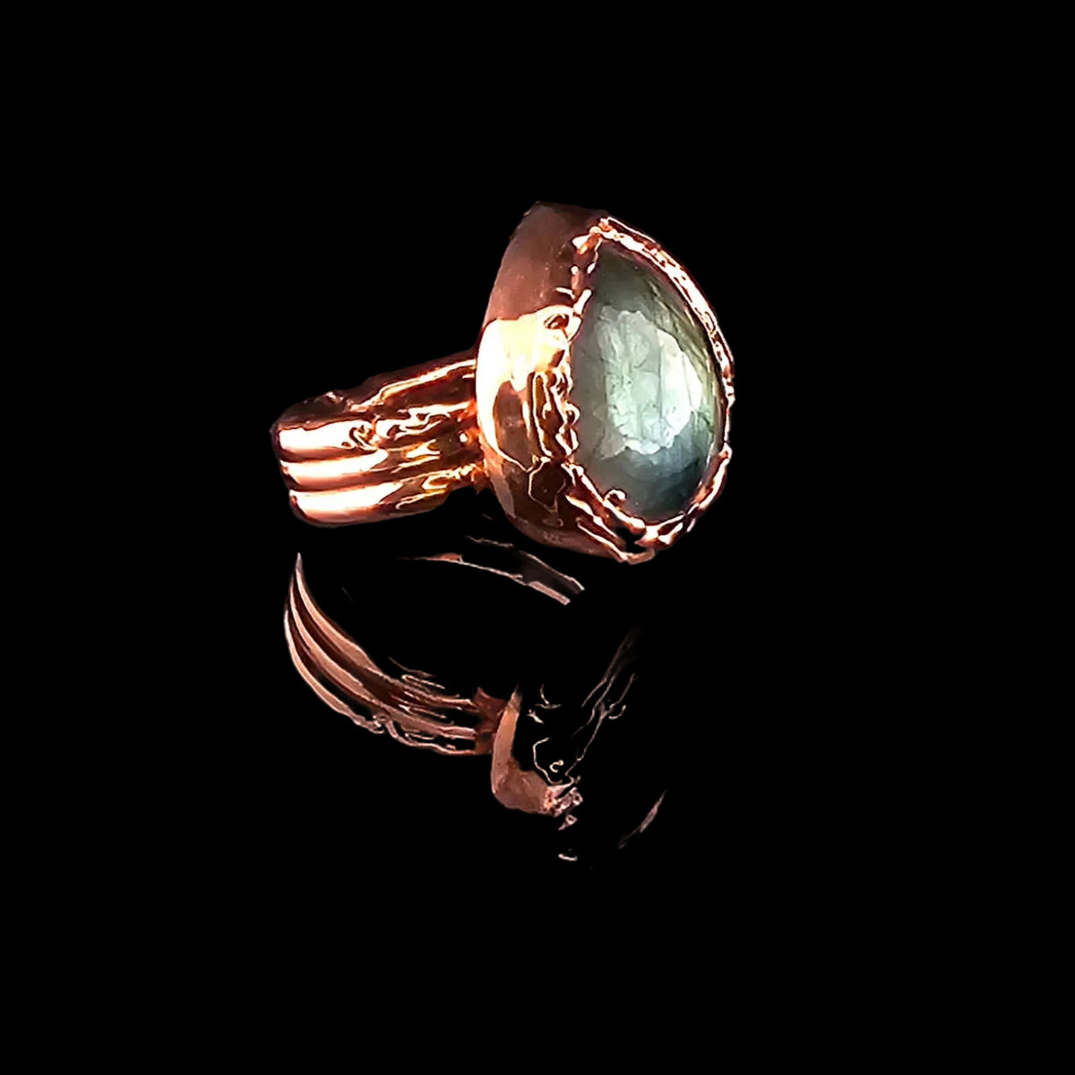 Angled side view of a handcrafted copper labradorite ring showing the faceted gemstone, organic setting and split band.