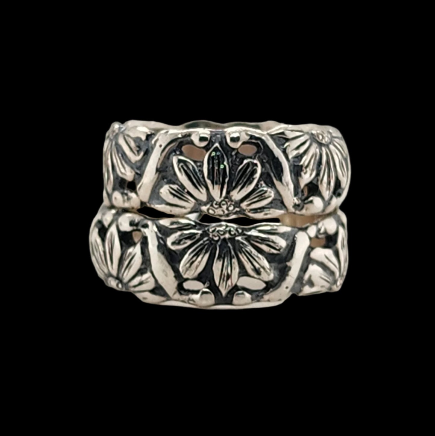 Pair of silver floral-patterned rings on a light gray background