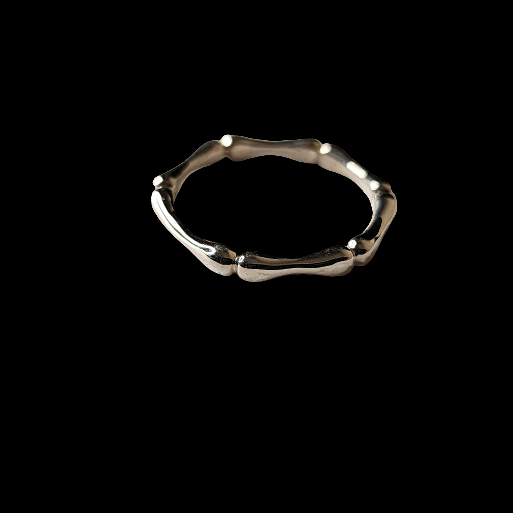 A silver ring with a bone-like, textured design on a black background, showcasing its polished finish and organic, sculptural details.