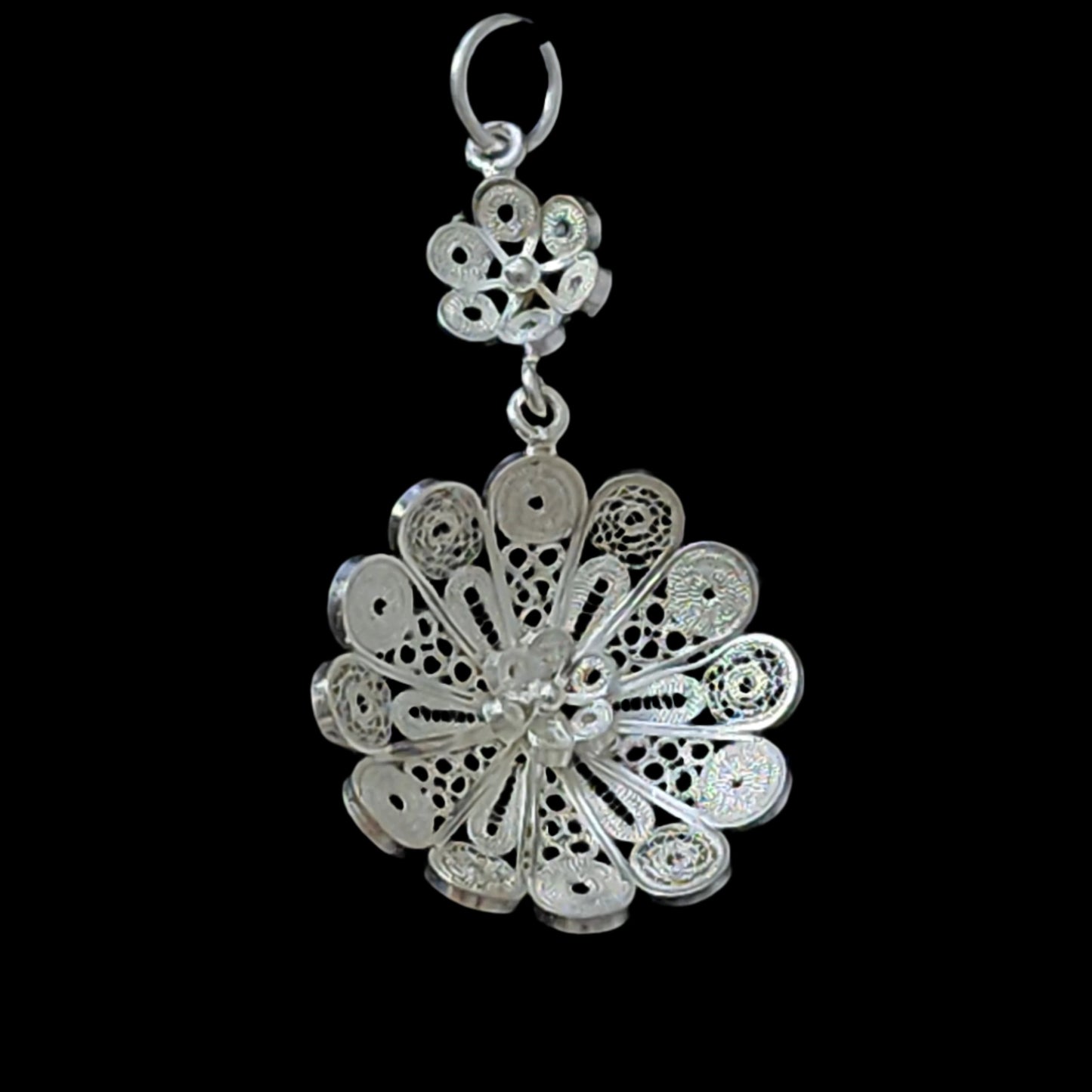 Single sterling silver filigree pendant with an intricate floral motif and delicate craftsmanship, displayed against a black background.
