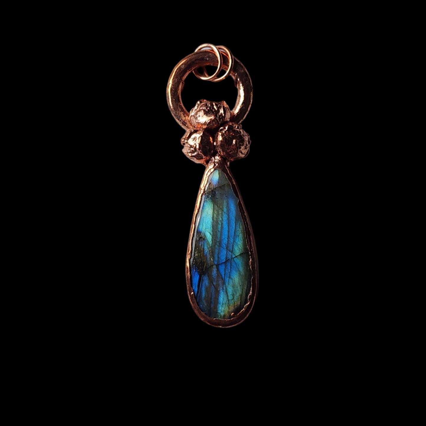 Copper pendant with a vibrant labradorite teardrop gemstone and natural buds, displayed on a black background, showcasing its glowing iridescence.