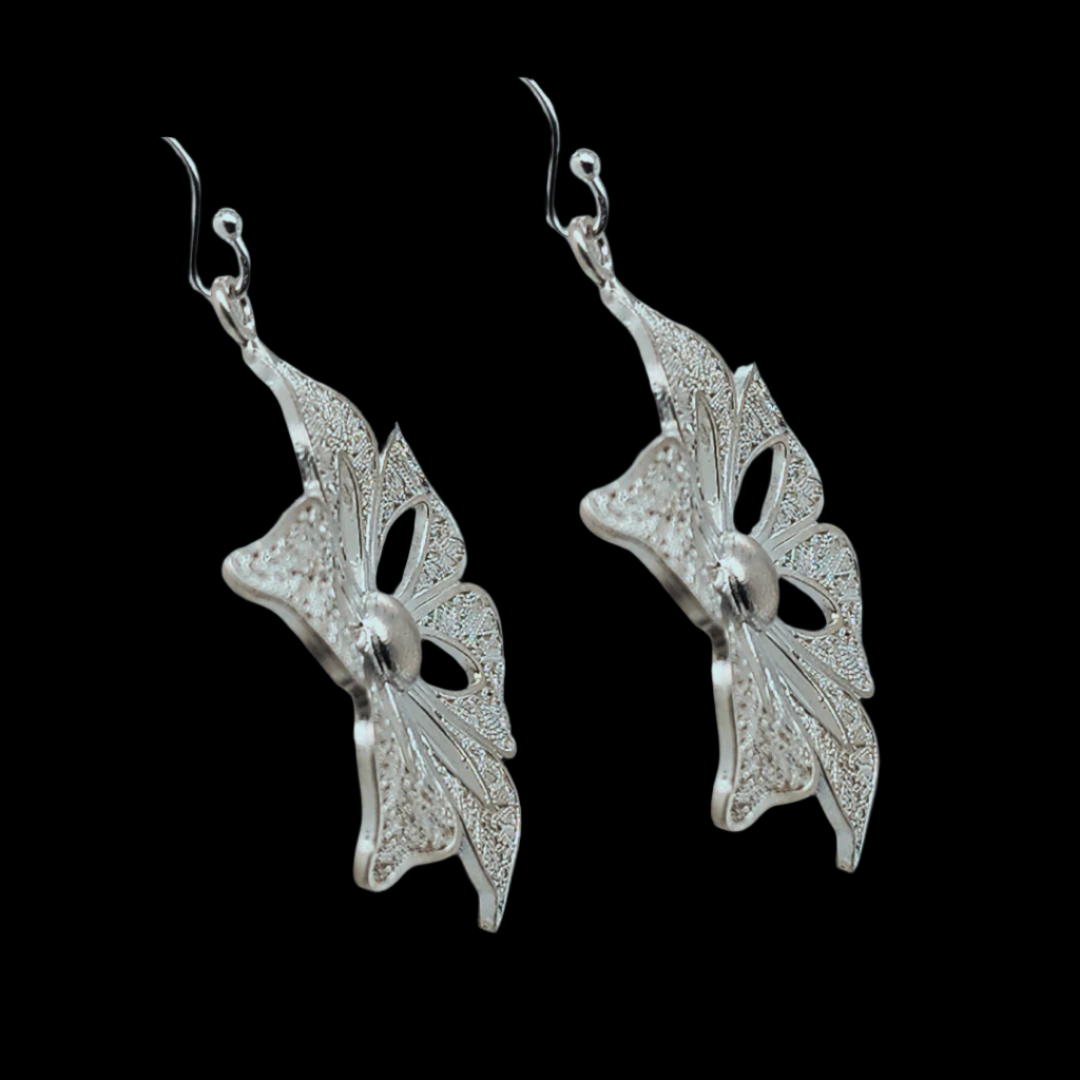 a side view of the silver earrings, with petal cutouts, filigree design inside and a polished central bead.