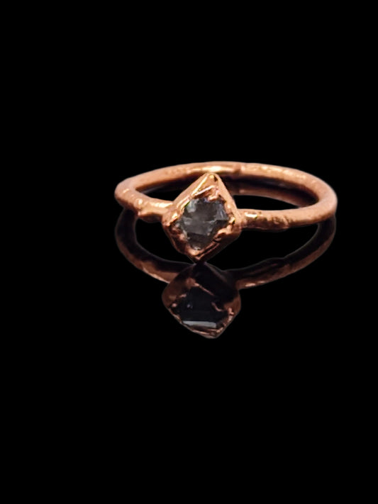 Handcrafted raw copper ring featuring a natural Herkimer diamond centerpiece, displayed against a black background with a reflective surface.