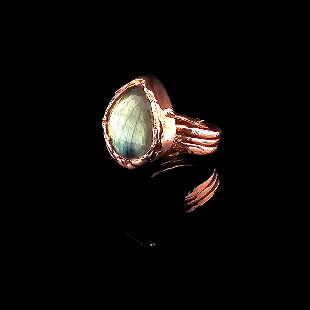 Side view of a faceted labradorite and electroformed copper statement ring showing the raised setting and split band.