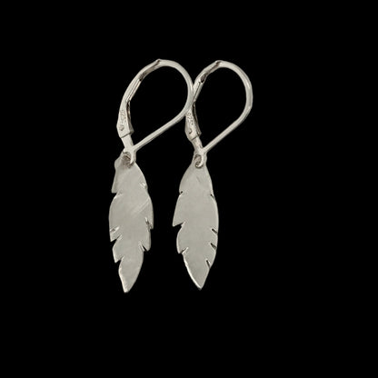 Pair of sterling silver feather drop earrings with a brushed finish, hanging from sterling silver leverback hooks on a black background.