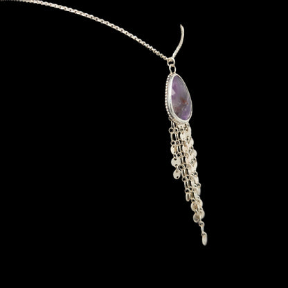 Side view of a sterling silver necklace featuring a faceted teardrop-shaped amethyst pendant with cascading silver chain fringe, displayed against a black background.