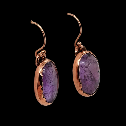 Handcrafted copper earrings featuring raw amethyst stones, displayed against a black background, showcasing their rustic and earthy design.