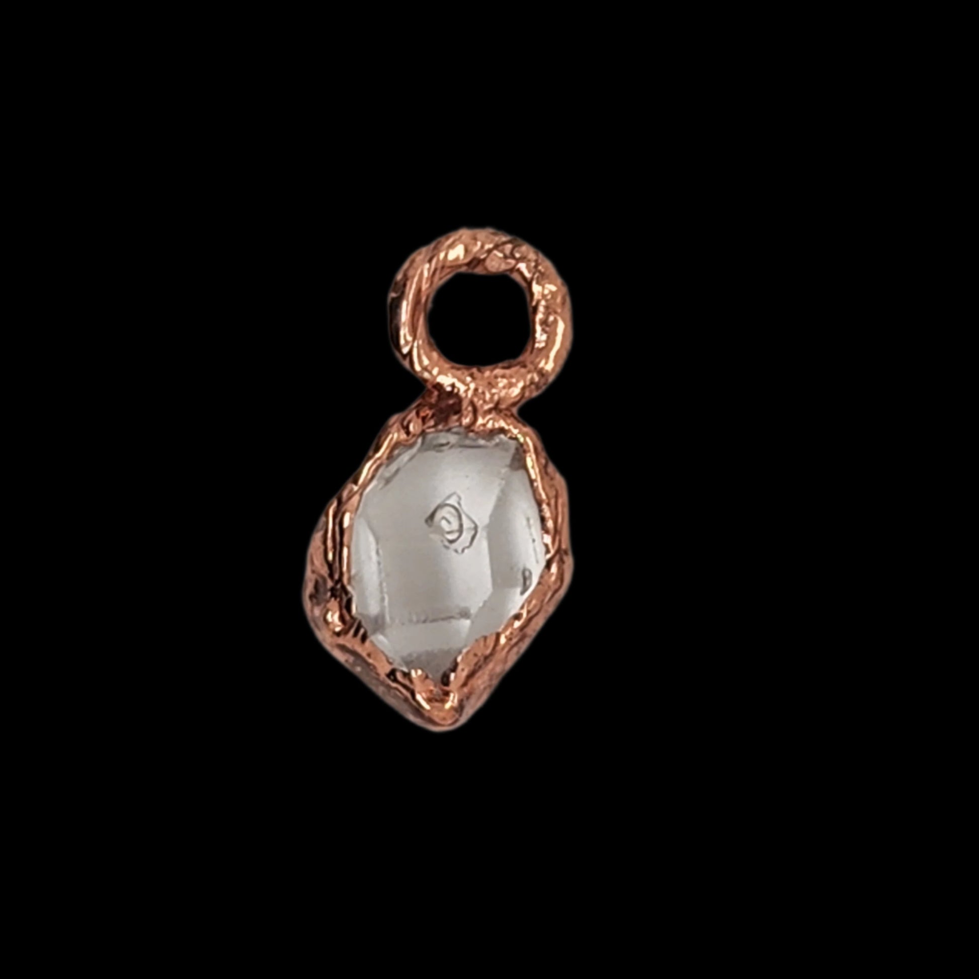 Top-down view of a copper pendant with a raw crystal gemstone, highlighting the organic setting and reflective surface of the stone.