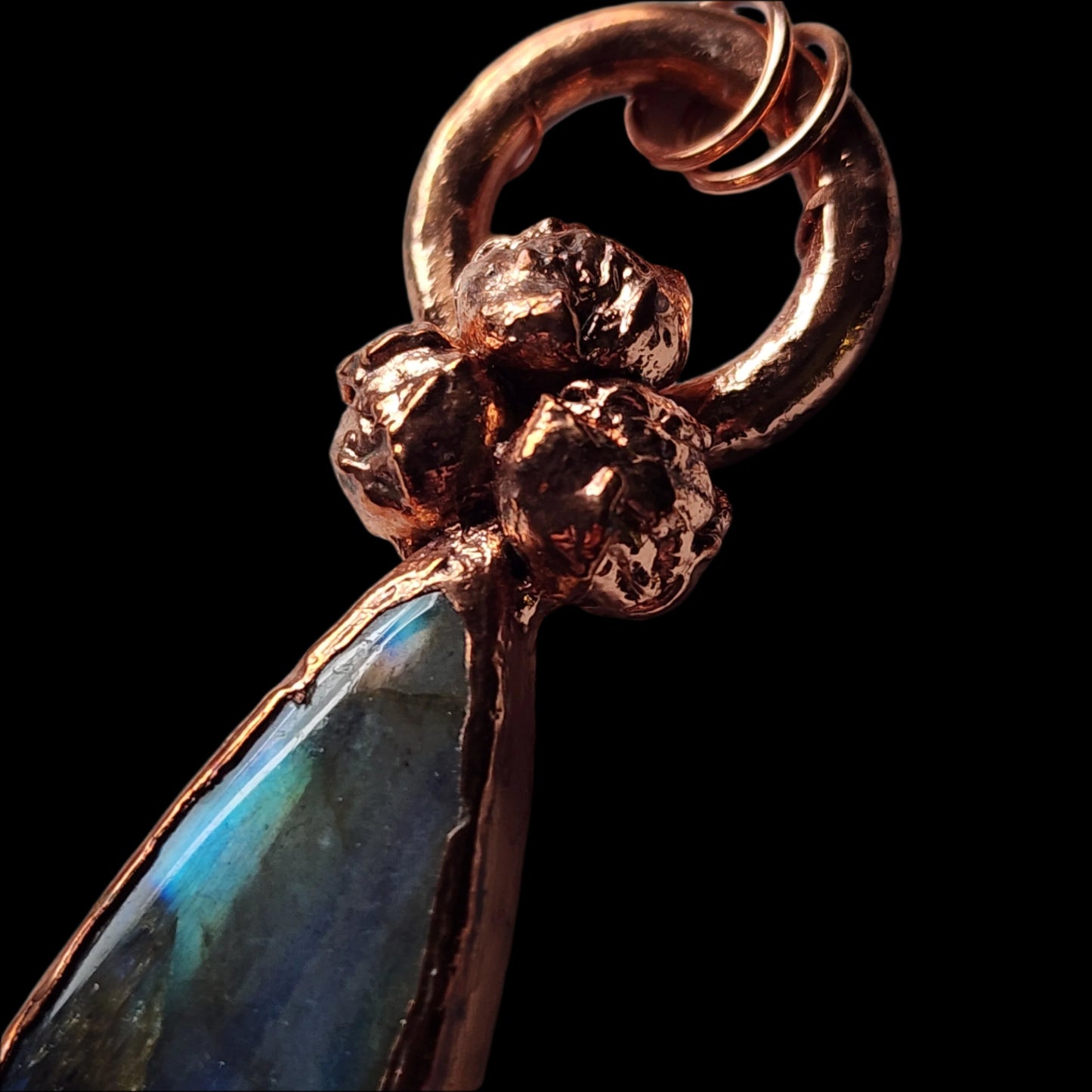 Close-up of the copper pendant, focusing on the detailed natural buds and the radiant labradorite gemstone