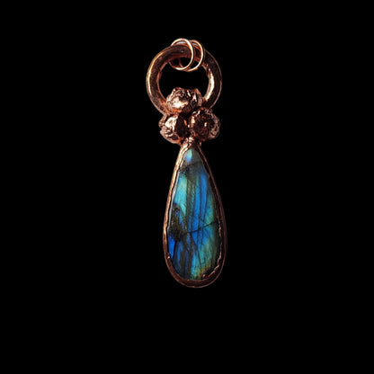  Copper pendant with a vibrant labradorite teardrop gemstone and natural buds, displayed on a black background, showcasing its glowing iridescence.