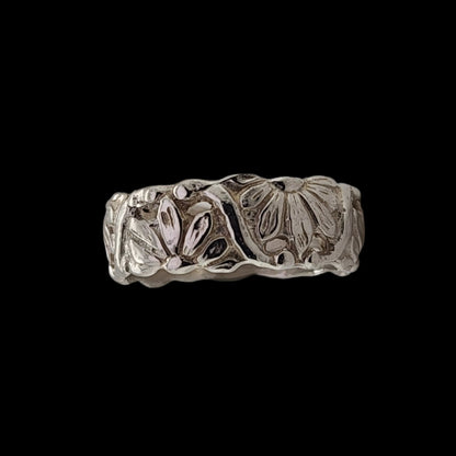 Handcrafted sterling silver floral ring with intricate engraved flower and leaf designs, displayed against a black background.